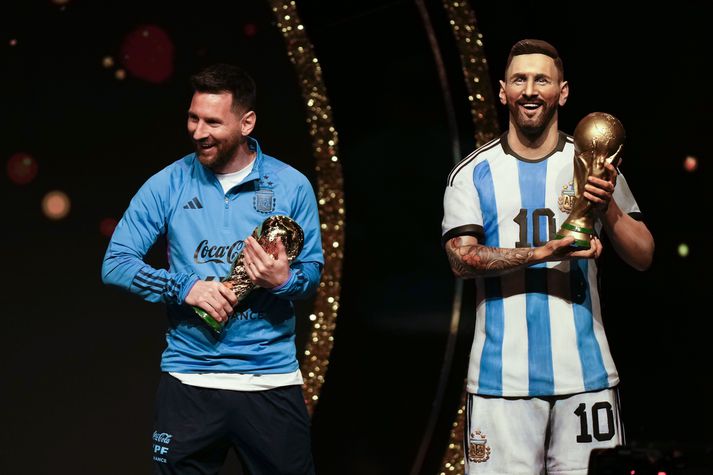 Lionel Messi með eftirmynd af HM-bikarnum og við styttu af honum sjálfum.
