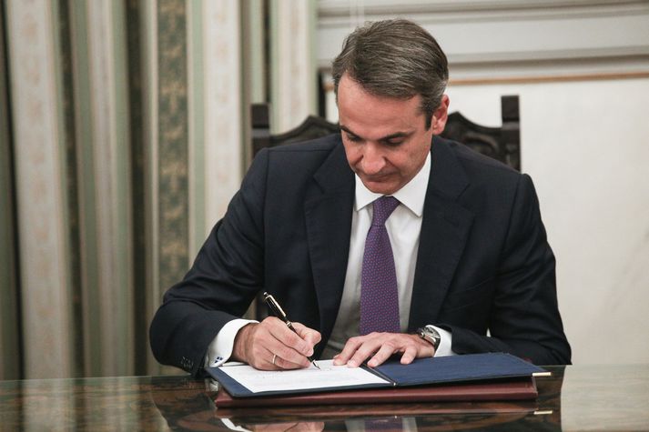 Mitsotakis skrifar undir.