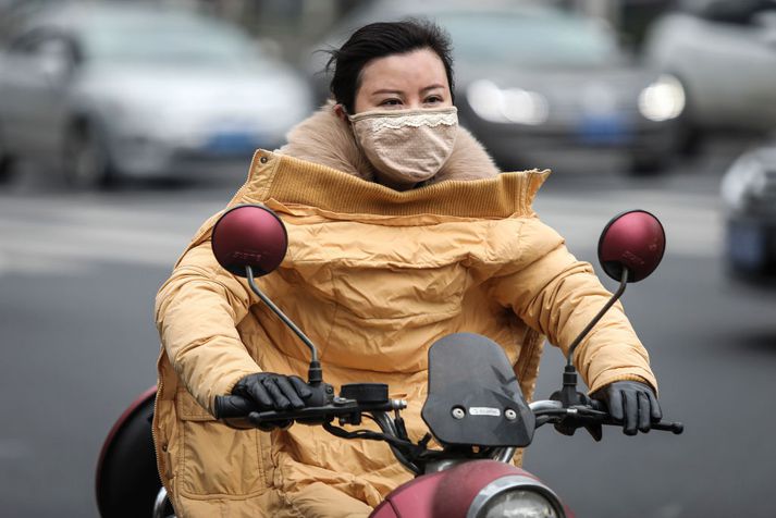 Ökumaður vespu í Wuhan með grímu fyrir vitunum. Talið er að veira eigin upptök sín í borginni.