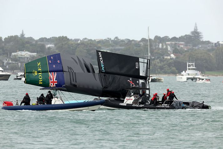 Viðbragðsaðilar við gjörónýtan bát nýsjálenska liðsins. Einn liðsmaður þess braut báða fætur í slysinu.