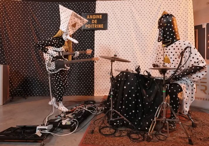 Angine de Poitrine hefur slegið í gegn á netinu undanfarið. Á sviðinu mætir tvíeykið  doppóttum búningum  og með grímur vopnuð framandi tónlist sem leikin er með hljóðfærum sem gerir þeim kleift að spila svokallaða míkrótóna. .