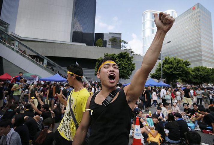 Einn þeirra sem hafa krafist lýðræðisumbóta í Hong Kong hrópar slagorð yfir hóp mótmælenda á götu skammt frá höfuðstöðvum stjórnvalda í Hong Kong. 