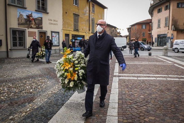 Fólk með andlitsgrímur við jarðarför í Bergamo þann 7. mars síðastliðinn. Þá höfðu 3900 greinst sýktir og 197 látist af völdum veirunnar á Ítalíu. Tölurnar hafa síðan margfaldast og er staðan hvergi verri í Evrópu.