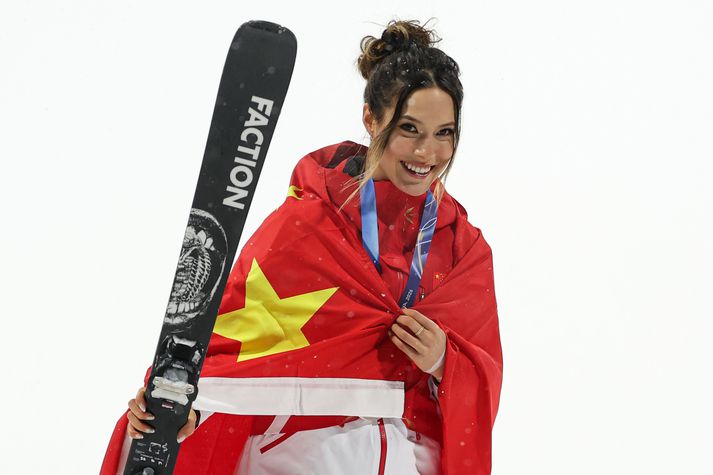 Eileen Gu sést hér umvafinn kínverska fánanum og með Ólympíusilfur um hálsinn.