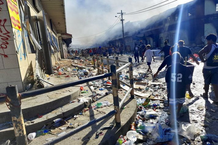 Mótmælendur ganga um götu Kínahverfisins í Honiara, höfuðborg Salómonseyja í dag. Óeirðir, íkveikjur og gripdeildir hafa átt sér stað í mótmælum undanfarinna daga.