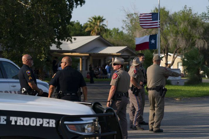 Lögreglumenn fyrir utan útfararstofu í Uvalde í gær. Í bakgrunni blakta fánar Bandaríkjanna og Texas í hálfa stöng. Viðbrögð lögreglu við skótárásinni í síðustu viku sæta harðri gagnrýni.