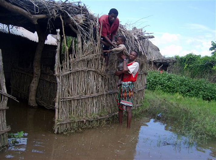 Maður bjargar dreng af þaki strákofa í Austur-Afríku.