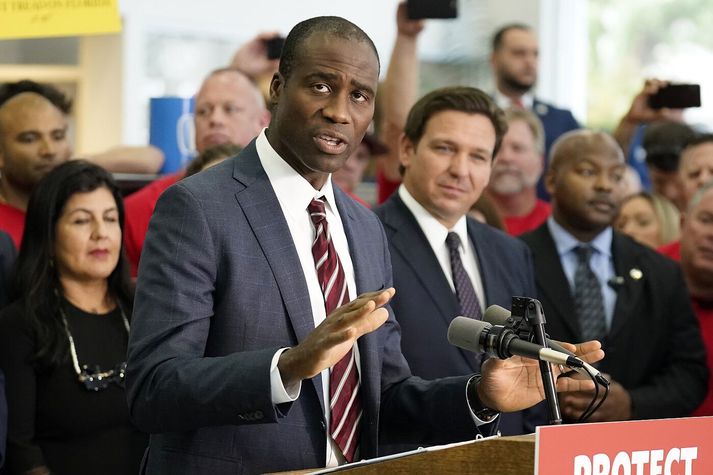 Joseph Ladapo, heilbrigðisráðherra Flórída, á blaðamannafundi í dag. Fyrir aftan hann má sjá Ron DeSantis, ríkisstjóra.