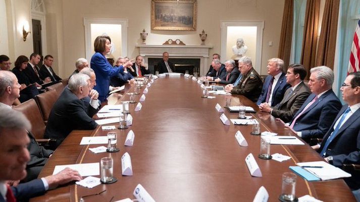 Nancy Pelosi stendur við borðið á fundi Demókrata Donald Trump.