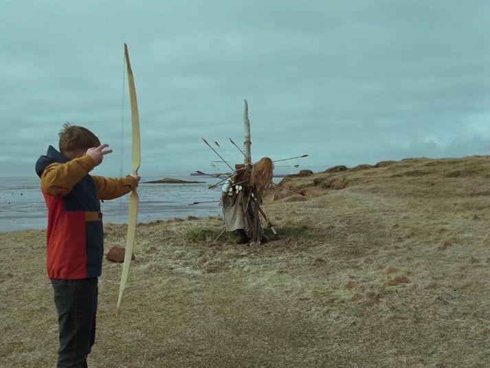 Systkinin skemmta sér við að skjóta í riddarann sem þau hafa byggt.