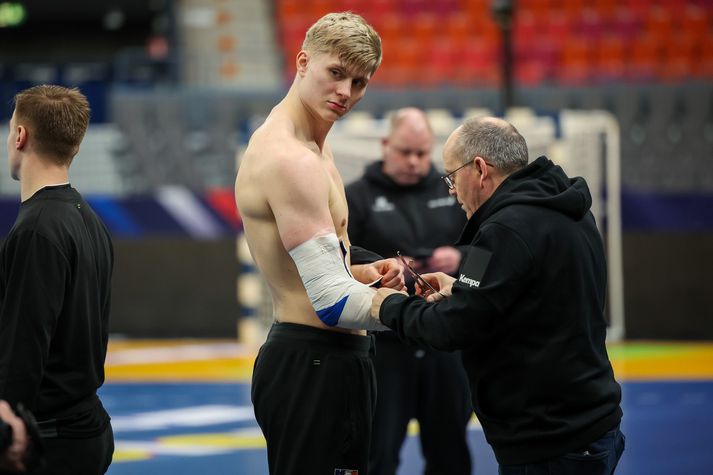 Viktor Gísli spilar með sérhannaða olnbogahlíf og það er talsverð vinna að teipa hana á og taka hana svo af eftir æfingu. Elís Rafnsson sjúkraþjálfari er öllu vanur og leysir verkefnið fagmannlega.