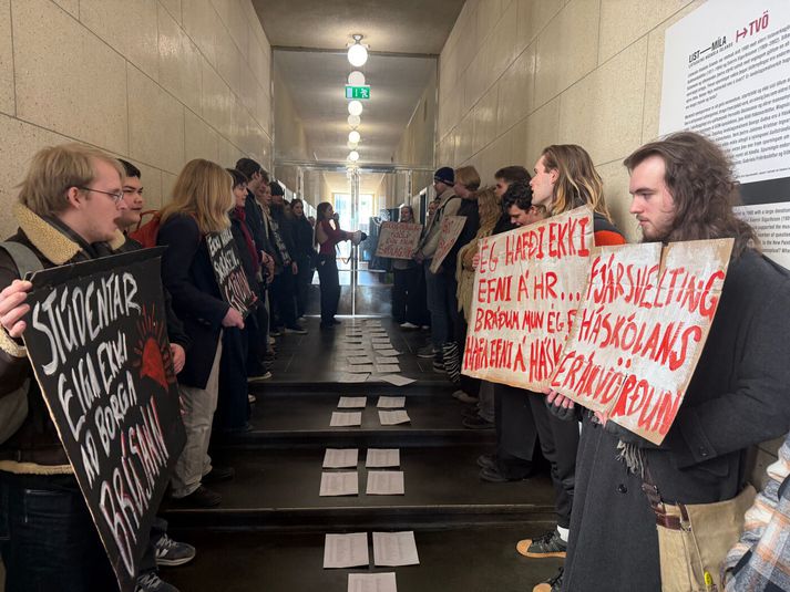 Nokkrir tugir stúdenta komu sér fyrir með mótmælaspjöld í aðalbyggingu Háskóla Íslands í aðdraganda fundarins sem hófst klukkan 13 og lauk um fjögurleytið.