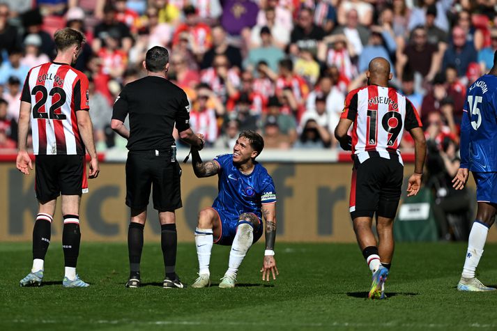Michael Oliver dómari hjálpar Enzo Fernandez, fyrirliða Chelsea, á fætur í leiknum í dag.