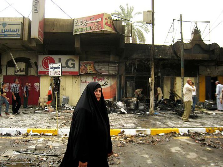 Kona stendur á götu í Bagdad þar sem bílasprengja sprakk á sunnudag; sex létust.