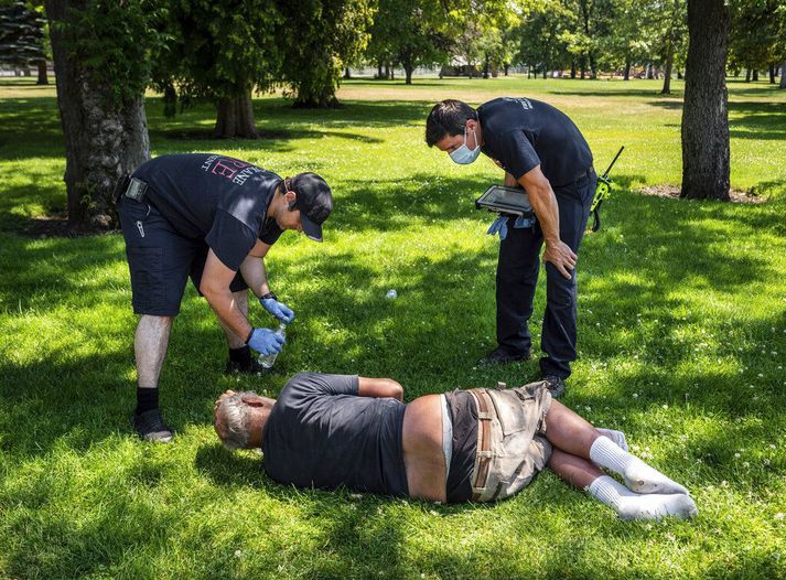 Hitabylgjan á vesturströnd Norður-Ameríku hefur leikið fólk grátt. Sjúkraliðar huga að manni sem hitinn hefur borið ofurliði í garði í Spokane í Washington í Bandaríkjunum.