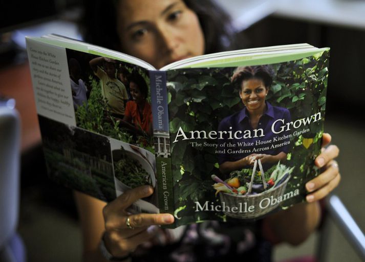 Hér flettir kona blöðum garðyrkjubókarinnar. Kápu hennar prýðir Michelle Obama sjálf með körfu fulla af grænmeti.
