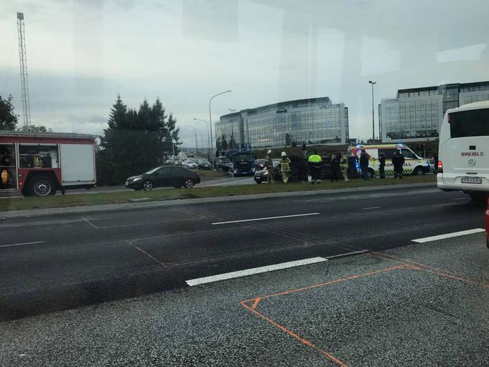 Bíllinn hafnaði upp á umferðareyju við gatnamótin og lá þar á hliðinni þegar viðbragðsaðila bar að garði.