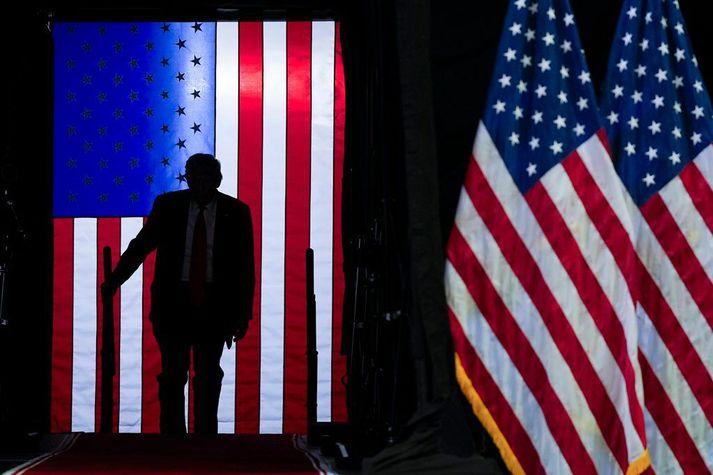 Donald Trump gengur hér inn á svið stuðningsmannafundar síns í gær.