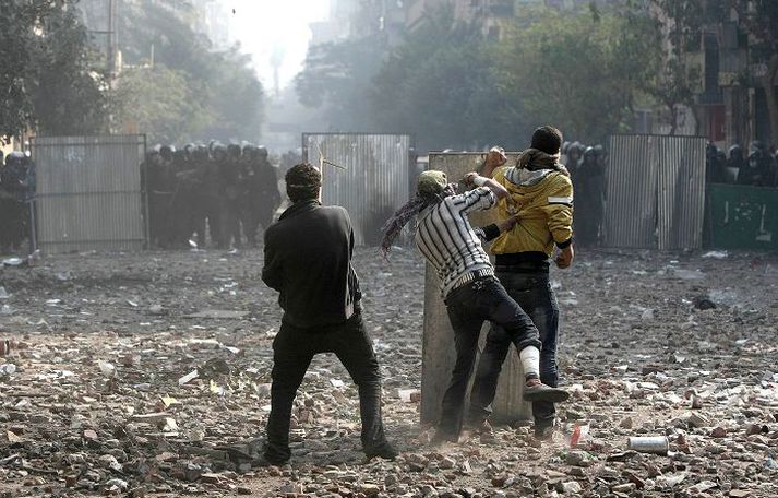 Nokkrir mótmælendur skýla sér bak við skjöld á Tahrir-torgi í Kaíró, en lögreglan bíður átekta. Mótmælendur áttu von á gasi frá lögreglu og voru við öllu búnir.nordicphotos/AFP