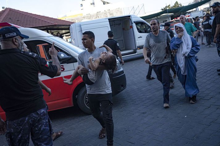 Palestínskur maður með særða stúlku við sjúkrahús í Gasaborg.