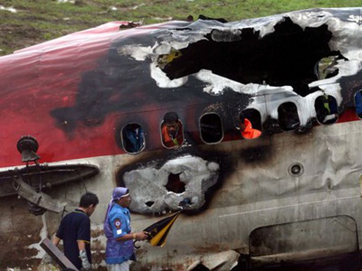 Embættismenn skoða flak vélarinnar í Phuket. Slysið er versta flugslys í Taílandi í áratug.