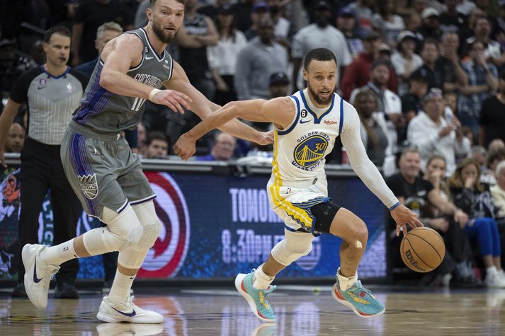 Stephen Curry hjá Golden State Warriors fer framhjá Domantas Sabonis í Kings-liðinu .