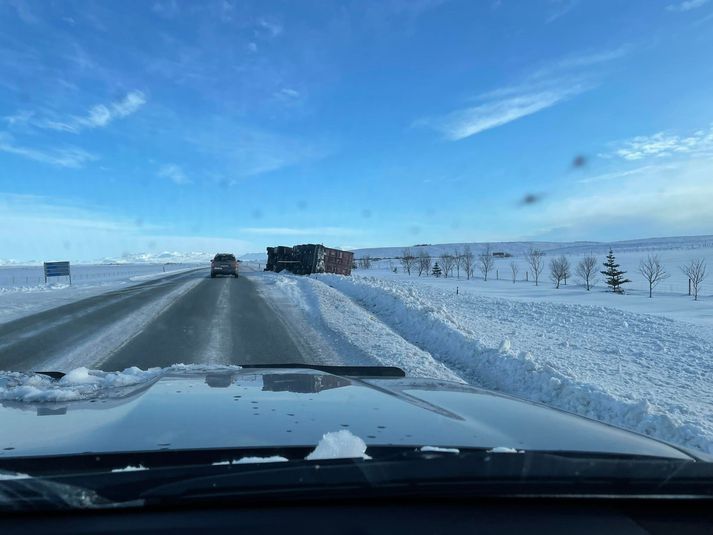 Bíllinn liggur úti í vegkantinum á Hringveginum austan Þjórsár.