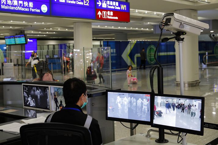 Heilbrigðisstarfsmaður fylgist með farþegum á alþjóðaflugvellinum í Hong Kong. Grannt hefur verið fylgst með mögulegri útbreiðslu nýju veirunnar.