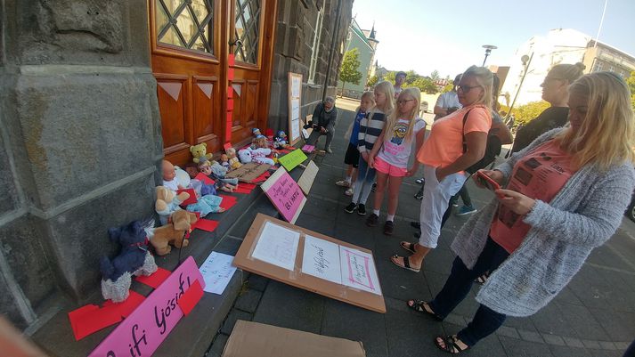 Mótmælendur gáfu ríkisstjórninni rauða spjaldið vegna stöðunnar í deilunni en spjöld mótmælenda sjást hér ásamt böngsum, leikföngum og kröfuspjöldum sem raðað var á tröppur þinghússins.