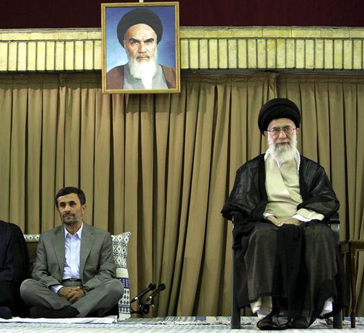 Mahmoud Ahmadinejad forseti situr með krosslagða fætur en æðsti leiðtoginn Ali Khameini á stól. Yfir gnæfir mynd af byltingarleiðtoganum Khomeini, forvera Khameinis. Mynd/AP