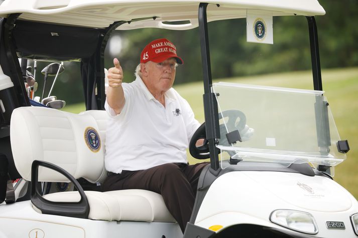 Donald Trump undir stýri á golfbíl á golfvelli sínum í New Jersey.