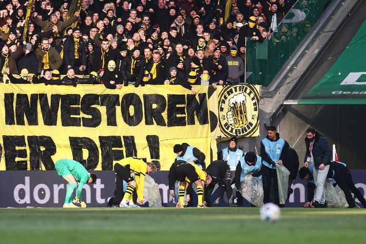 Leikmenn Dortmund hjálpa til við að fjarlægja súkkulaðið af vellinum.