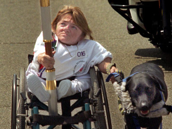 Hundurinn Roamer dregur Melanie Watson áfram eftir Western Avenue í Atlanta í Georgíu í tengslum við opnunarathöfn Ólympíuleikanna.