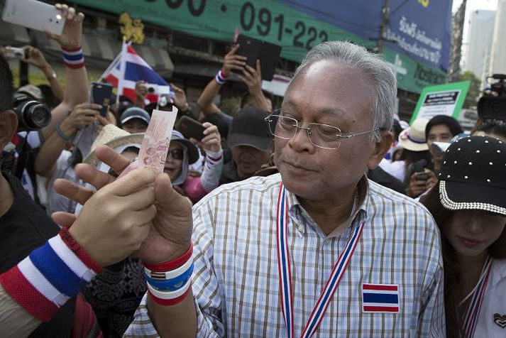 Suthep Thaugsuban, leiðtogi mótmælenda, tekur við seðli frá einum stuðningsmanna sinna.