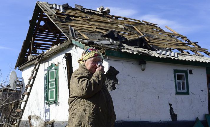 Ónýtt heimili. Tárvot eldri kona stendur fyrir utan húsið sitt, sem farið hefur illa út úr átökunum í Úkraínu.