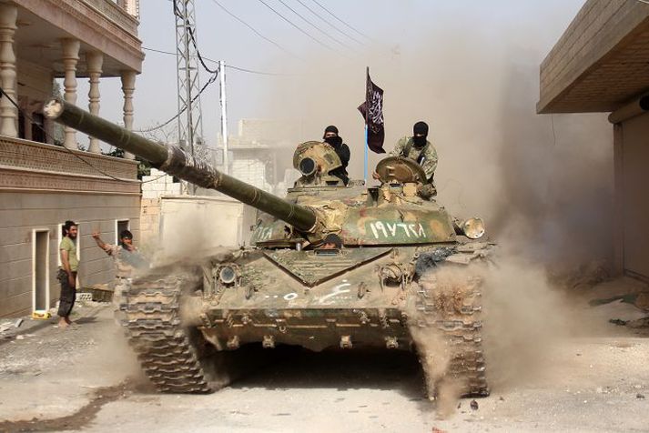 Uppreisnarmenn keyra inn í borgina Idlib á skriðdreka í mars síðastliðnum.