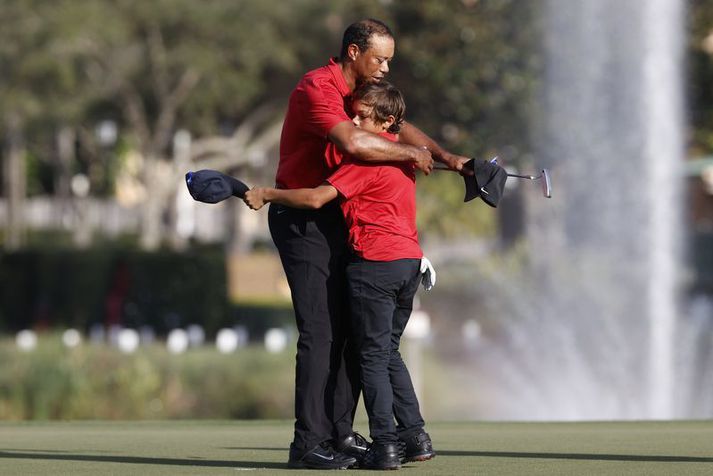 Tiger Woods faðmar son sinn Charlie Woods efir lokapúttið á átjándu holunni.