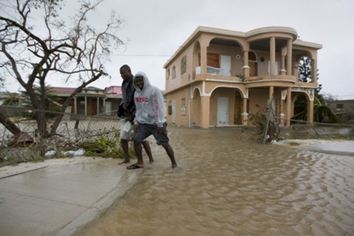 Tveir menn á gangi á eynni Providenciales í Turks- og Caicos-eyjaklasanum þar sem allt er á floti.