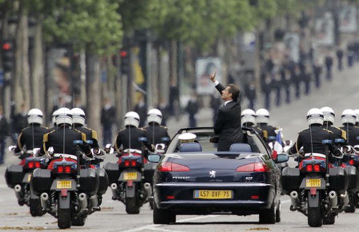 Nicolas Sarkozy veifar til fólksins sem kom til að fylgjast með þegar hann ók niður Champs Elysees eftir embættistökuna í morgun.