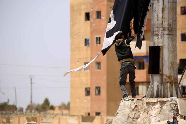 Meðlimur SDF tekur niður fána ISIS í Tabqa í síðasta mánuði.