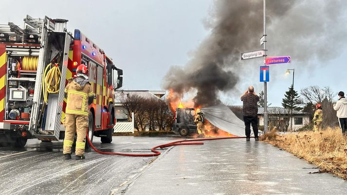 Frá vettvangi í dag þar sem sjá má slökkviliðið draga teppi yfir bílinn.