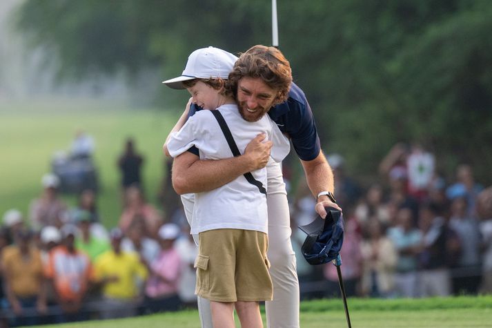 Tommy Fleetwood faðmar son sinn, Frankie, eftir sigurinn á DP World India Championship.