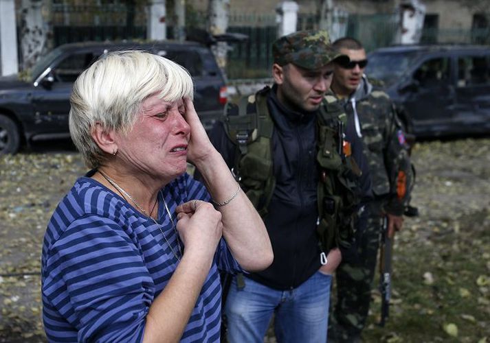 Úkraínsk kona grætur fyrir framan skóla sem varð fyrir skemmdum í árás uppreisnarmanna í borginni Donetsk.