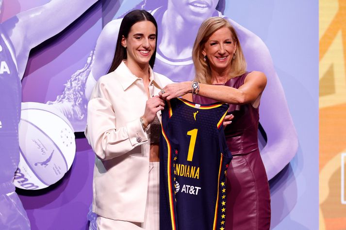 Caitlin Clark stllir sér upp með Indiana Fever búninginn og við hlið Cathy Engelbert, hæstráðanda í WNBA deildinni.