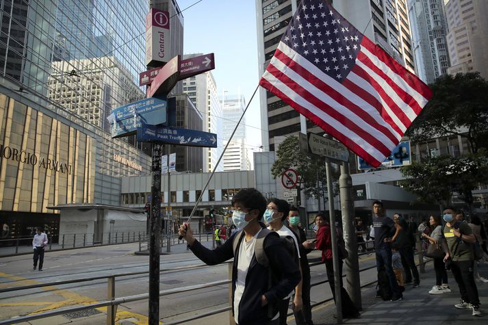 Mótmælandi veifar fána Bandaríkjanna í Hong Kong í morgun.