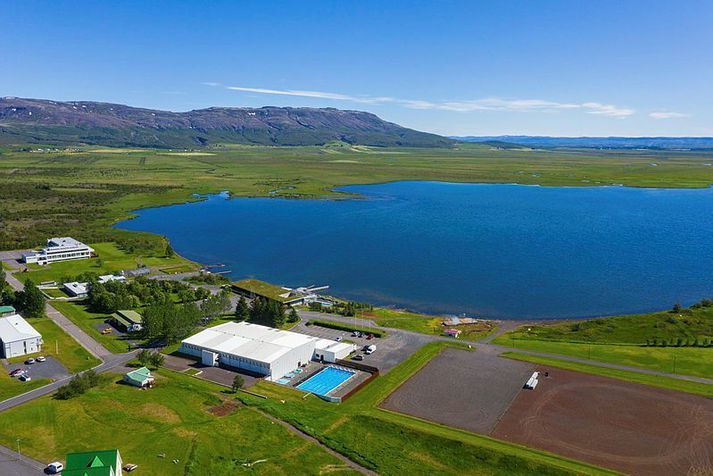 Torfklætt Fontana Spa stendur við fagurblátt Laugarvatnið á góðviðrisdegi.