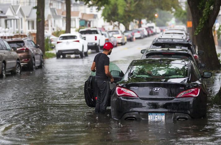 Íbúi í Queens í New York athugar með bifreið sína eftir mikið regn í kjölfar Henri.