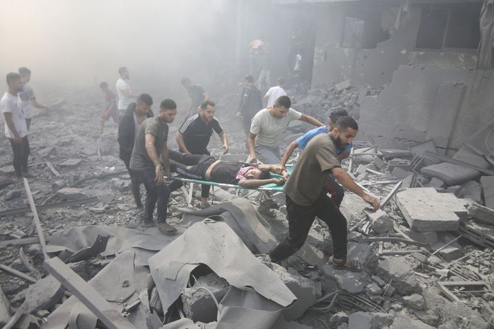 Palestínumenn aðstoða særða í rústum eftir loftárásir Ísraelsmanna í flóttamannabúðum sem kenndar eru við Rafah.