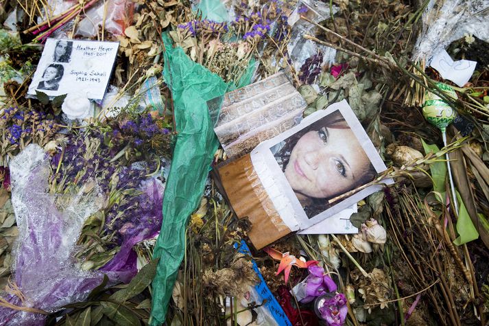 Mynd af Heather Heyer, konunni sem lést þegar maðurinn ók bíl sínum inn í hópinn, umkringd blómum og kertum.