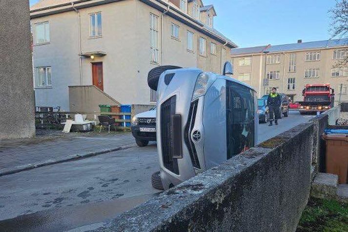 Bíllinn hafnaði á hliðinni í þröngri götunni.